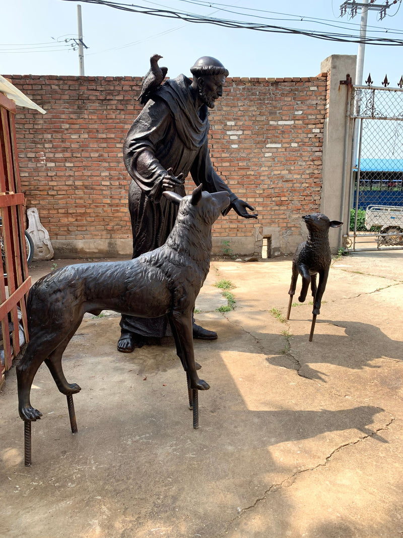 statue of st. francis with a dog and a lamb in an outdoor setting.
