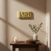 INRI plaque with bold, classical raised lettering on an ornate, scroll-shaped background in old world European style. Side Angle