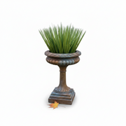 Ornate classical urn planter with fluted pedestal base and scalloped rim, featuring lush grass, old world European style