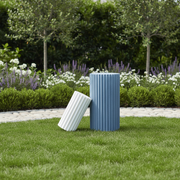 Fluted cylindrical vessels with classical Greek-inspired vertical ridges, one upright and one leaning beside it. Side Angle