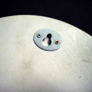 Keyhole escutcheon plate with two screws on a smooth, rounded surface, featuring simple, classical design elements.