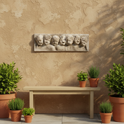 Baroque-style sculpted relief of seven cherubic faces with expressive features in an ornate, old world European design. Side Angle