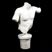 Classical Greek male torso sculpture with missing head and arms, displayed on an ornate fluted pedestal in old world European style. Different Angle