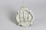 Crucifixion relief in ornate old world European style with classical figures and decorative Baroque frame topped with a cross.