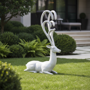 Reclining deer figurine with elongated, ornate antlers in a classical old world European style. Side Angle