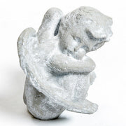 Seated cherub figurine with hands resting and large wings.