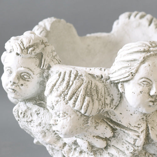 Ornate Baroque-style planter featuring sculpted cherub faces and classical old world European detailing around the rim. Different Angle