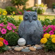 Owl statue with textured wings in an old world European style, flanked by a round topiary and a classical marble sphere. Side Angle