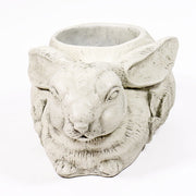 Rabbit-shaped planter with ornate floral motif, featuring old world European style and filled with yellow and orange flowers. Side View