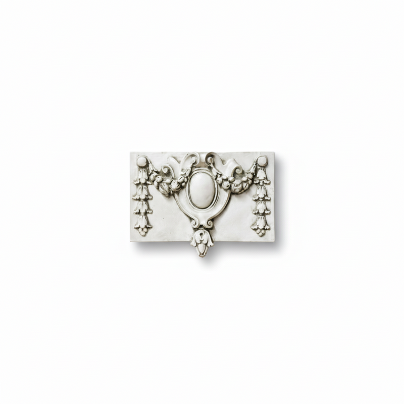 Ornate Baroque-style wall plaque with central oval medallion, floral garlands, and classical scrollwork detailing.