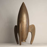 Rocket sculpture with smooth, streamlined form and three curved legs, featuring a minimalist, old world European retro-futuristic style. Side View
