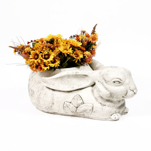 Rabbit-shaped planter with ornate floral motif, featuring old world European style and filled with yellow and orange flowers.