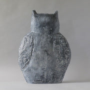 Owl statue with textured wings in an old world European style, flanked by a round topiary and a classical marble sphere. Side View
