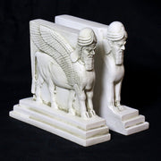 Sphinx-shaped ornate bookends with classical old world European detailing, supporting two upright hardcover books. Side Angle