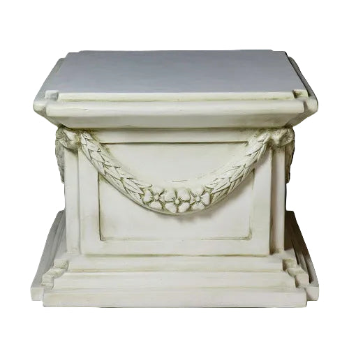 Classical pedestal with ornate garland detailing, square base, and stepped edges in an old world European architectural style.