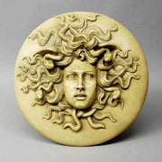 Medusa head relief with intricate serpentine hair, classical Greek style, ornate detailing, and dramatic facial expression.