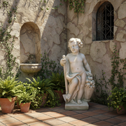 Cherub statue in classical Renaissance style holding a staff and leaning on a basket of fruit with ornate detailing. Side Angle