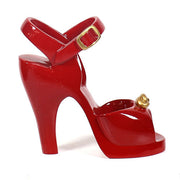 Red high-heeled shoe with an ornate Baroque-inspired gold accent and a classical ankle strap buckle design.